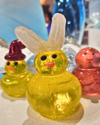 Glass ducks with assorted colors and accessories on a white surface