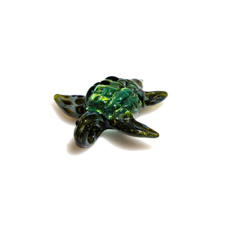 Green and black handmade glass turtle-shaped object on a white background
