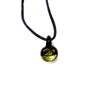 Black pendant with gold design on a black cord against a white background