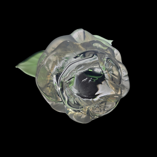 Clear glass rose with a green leaf on a black background